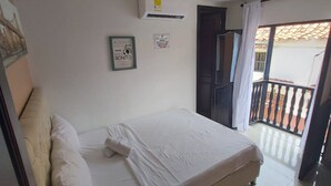 Un dormitorio con cama, aire acondicionado de pared, un cuadro enmarcado y una puerta que da a un balcón.