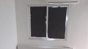 Una cama con cabecera acolchada, dos almohadas y un edredón enrollado.