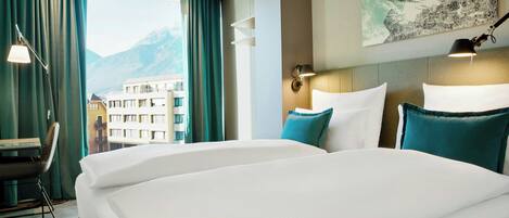 Habitación de hotel con una cama grande, un escritorio y vistas a la montaña.