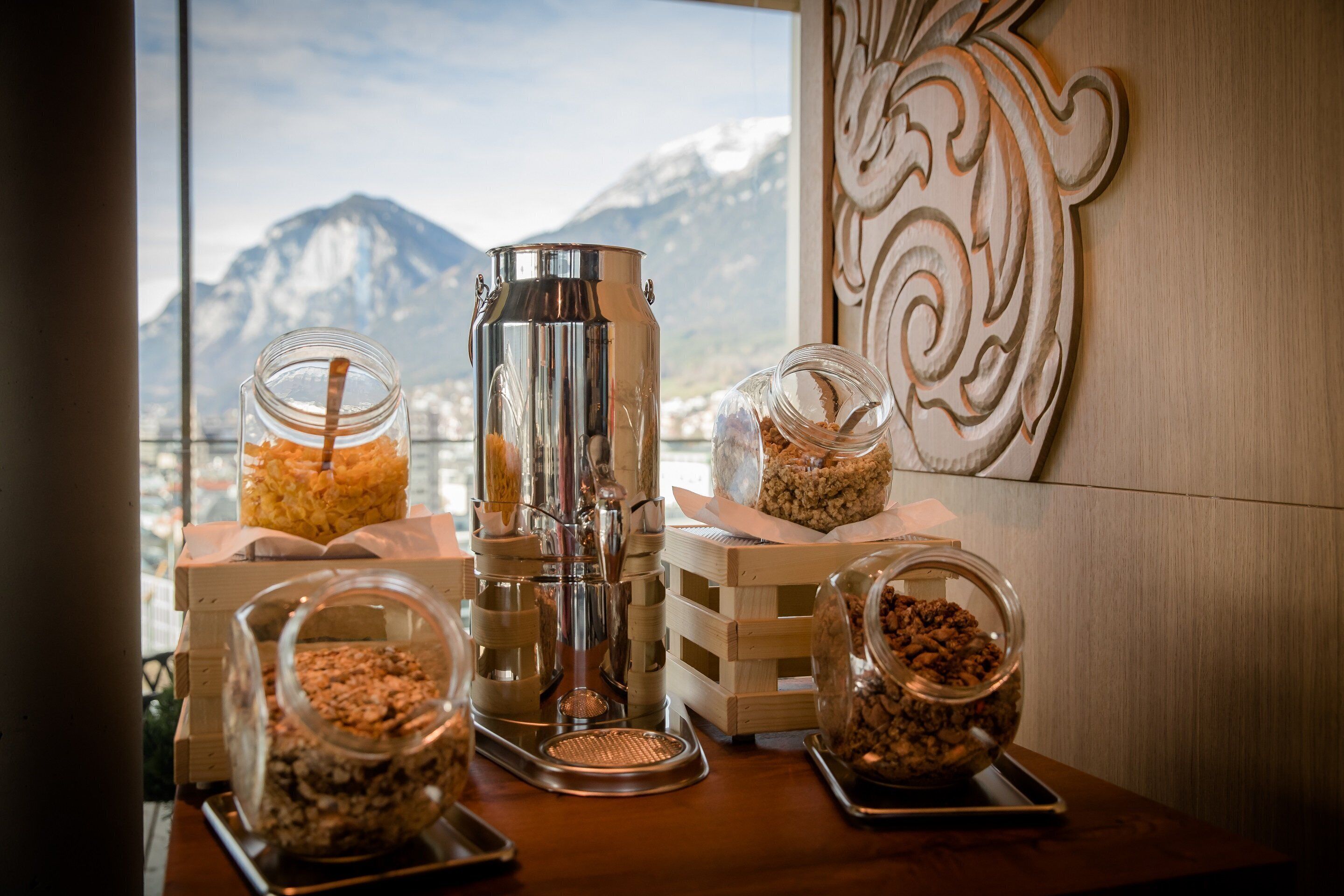 A coffee station with a grinder, jars of granola, and a view of mountains.