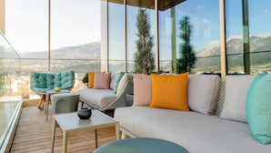 A modern lounge with a sofa, chairs, and a small table, featuring large windows with a mountain view. - Motel One Innsbruck (Innsbruck)
