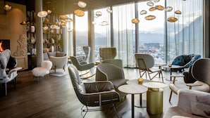 A modern lounge with leather chairs, round tables, and hanging light fixtures. - Motel One Innsbruck (Innsbruck)