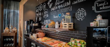 A breakfast buffet with various food items and a chalkboard with motivational messages.