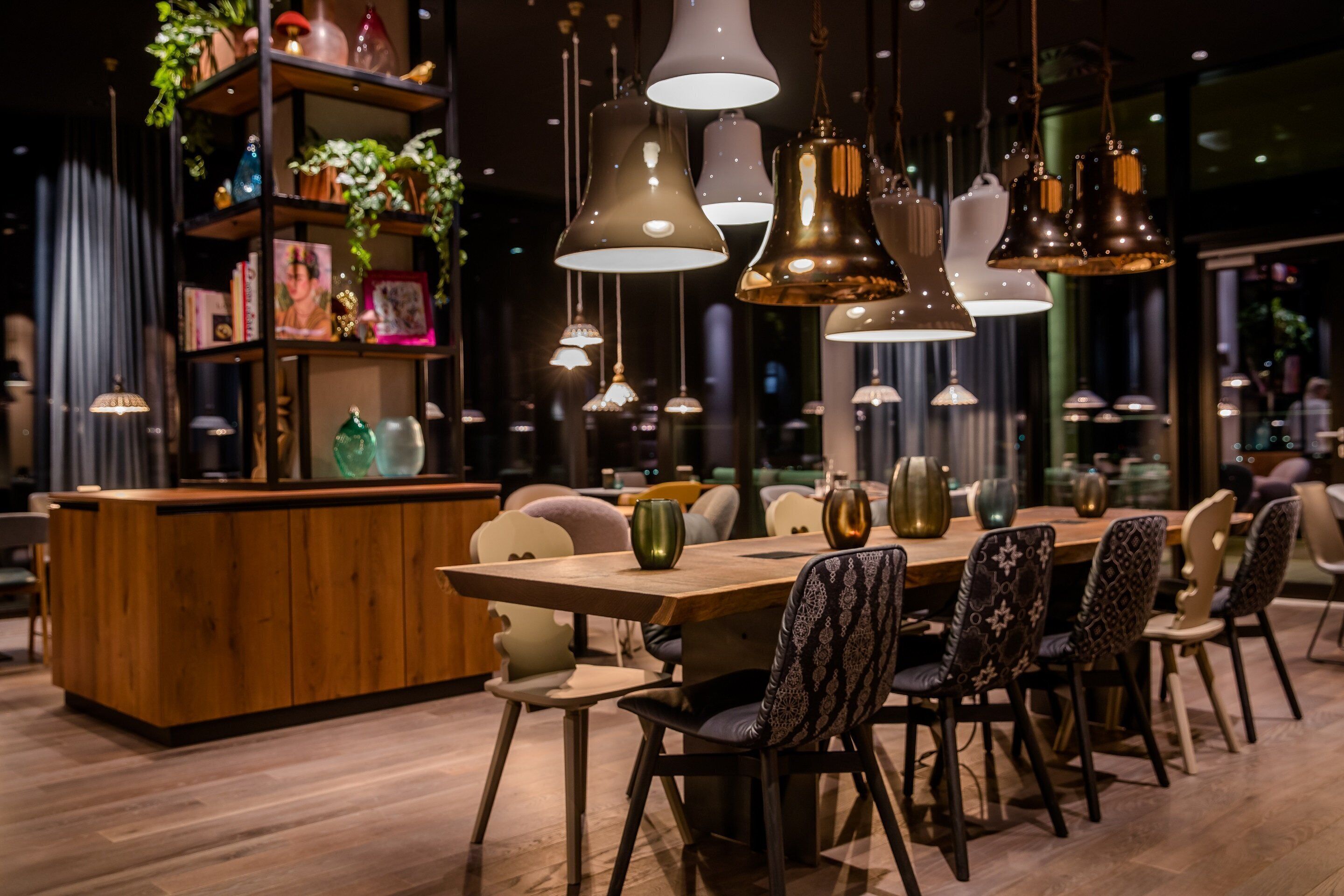 A modern dining area with a wooden table, patterned chairs, and pendant lighting.