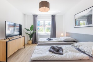 A hotel room with two beds, a TV, a plant, and a window with curtains. - Glück Auf Appartements Schleiermacherstr (Duisburg)