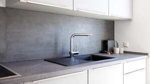 A modern kitchen with a sleek faucet, a built-in sink, and a grey backsplash. - Glück Auf Appartements Schleiermacherstr (Duisburg)