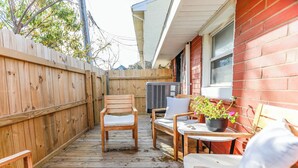 Eine Holzterrasse mit Gartenmöbeln, darunter Stühle und ein Tisch, sowie einem Blumentopf.