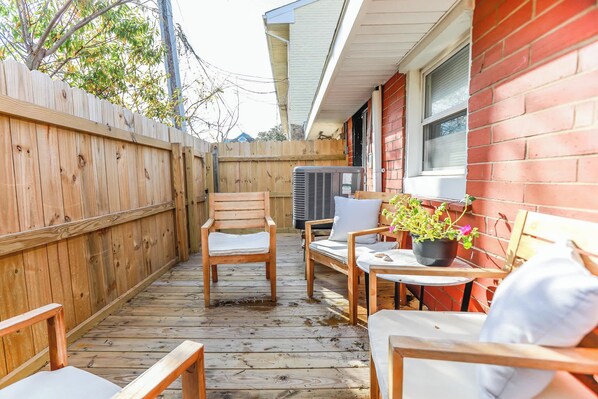 A wooden deck with outdoor furniture, including chairs and a table, and a potted plant.