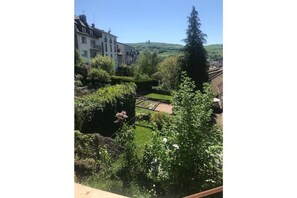 Uma área residencial com um jardim bem cuidado, um caminho e vista para uma colina ao longe.