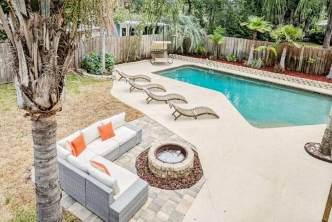 Um quintal com piscina, lareira e móveis para área externa.
