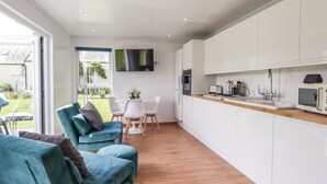 A modern kitchen with white cabinets, a wooden countertop, and a built-in microwave. - Moss of Bourach (Aberlour)