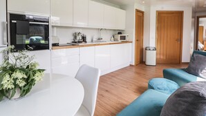A modern kitchen with white cabinets, a wooden countertop, and a dining area with a white table and chairs. - Moss of Bourach (Aberlour)