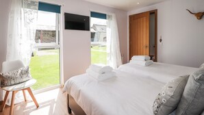 A bedroom with a large bed, a chair, a wooden door, and a view of the outside. - Moss of Bourach (Aberlour)