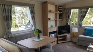 Interior acogedor de una caravana con sofá, mesa y televisor.