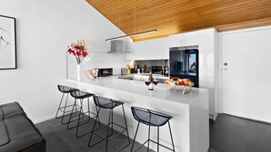 Une cuisine moderne dotée d’un îlot central, de tabourets de bar et d’un plafond en bois.