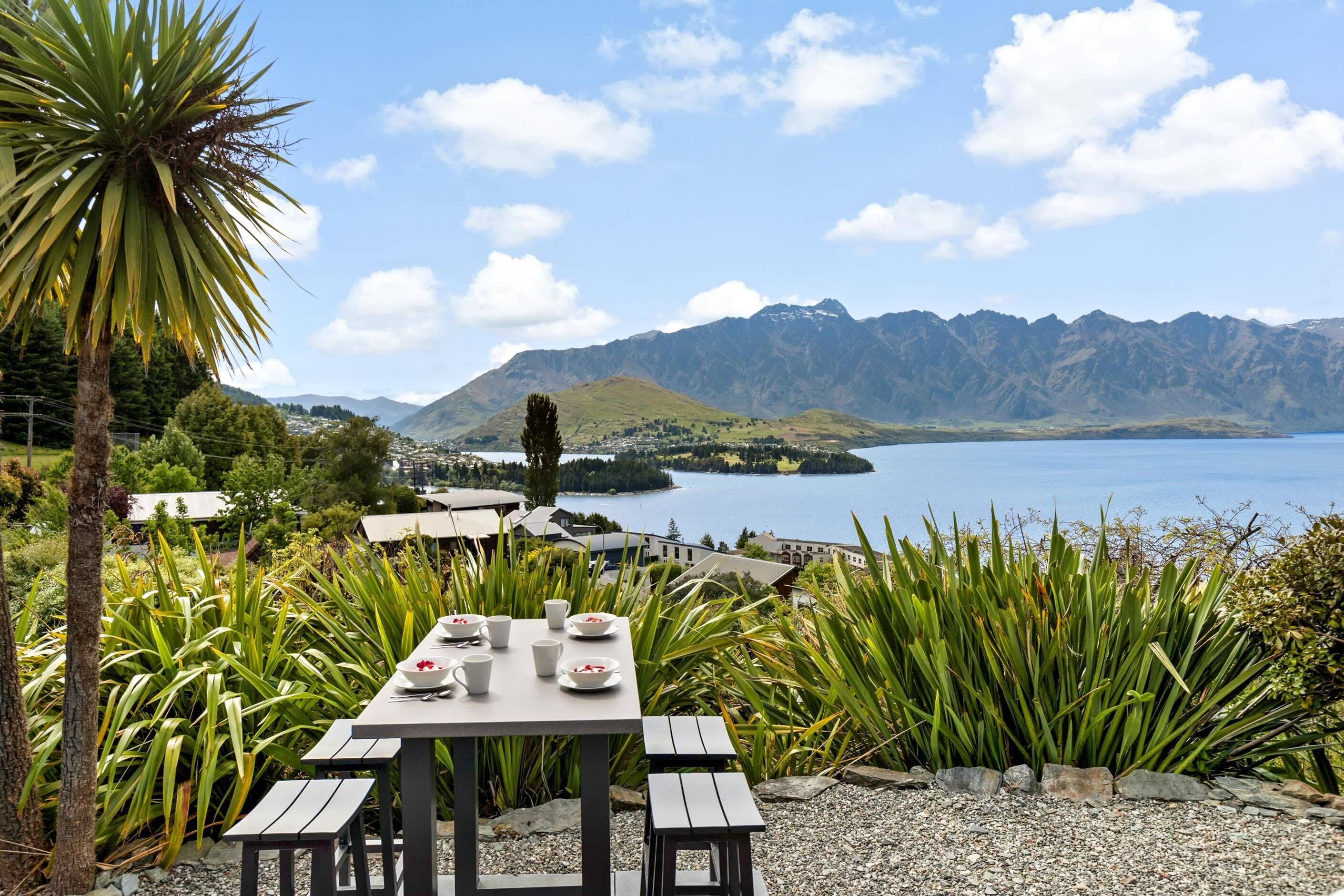A table set with cups and saucers, overlooking a lake and mountains.