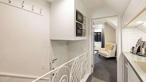 Et moderne køkken med indbyggede hårde hvidevarer, et lyst interiør og en trappe til et andet rum.