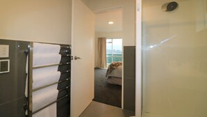 A hotel room with a shower, a bed with a blanket, and a view of the outdoors through the window. - CENTRAL CITY APARTMENT, FREE PARKING, BAY VIEWS (Queenstown)