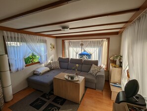 Ein gemütliches Wohnzimmer mit einer grauen Couch, einem Holztisch und einem gemusterten Teppich.