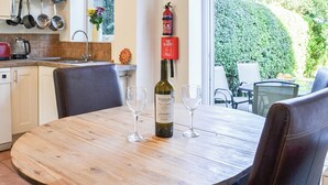 Una cocina con ollas colgantes, una manta ignífuga y una botella de vino sobre una mesa.
