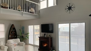 Un ampio soggiorno con camino, televisione e un balcone con vista.
