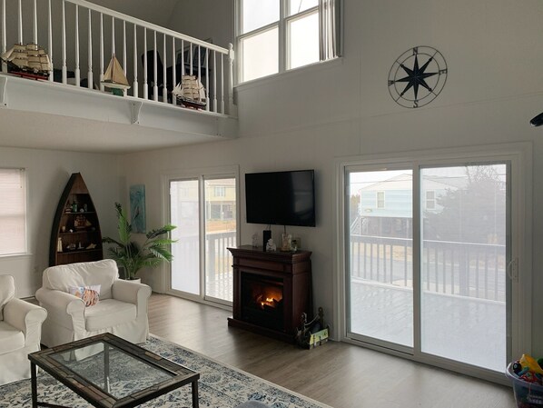 A spacious living room with a fireplace, a television, and a balcony with a view.