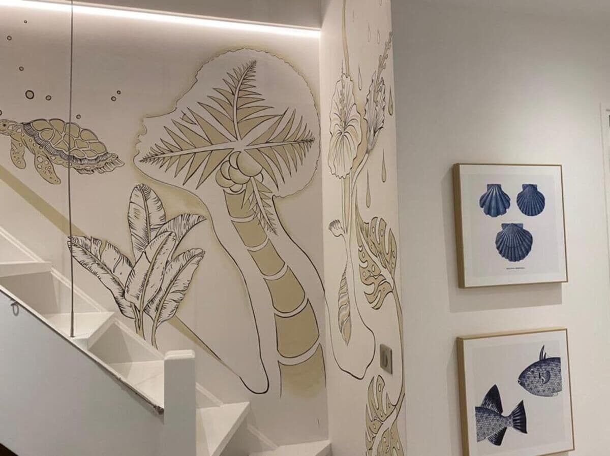 Un escalier orné d’une peinture murale représentant une tortue, des fougères et des fleurs.