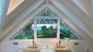 A bathroom with a skylight, two sinks, and storage baskets.