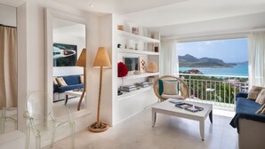 A modern living room with a balcony overlooking a coastal view.