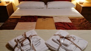 Ein ordentlich gemachtes Bett mit weißen Leinen und roten Kissen, ein dekorativer Kopfteil und zwei Nachttischlampen.