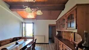 Ein Holztisch mit Stühlen, ein Fenster mit Vorhängen und ein Küchenbereich mit Schränken.
