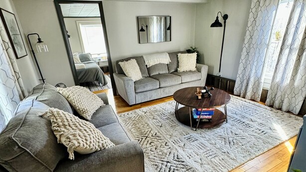 A modern living room with a grey sofa, a coffee table, and a patterned rug.