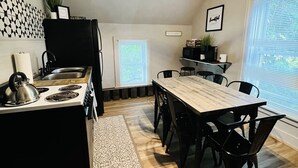 A modern kitchen with a dining area, featuring a stove, sink, and a dining table with chairs.