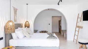 A modern bedroom with a large bed, two hanging lamps, a small round table with a drink, and a ladder against the wall.