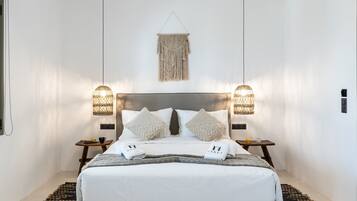 Un dormitorio moderno con una cama grande, dos mesitas de noche y un adorno colgante de macramé sobre la cama.