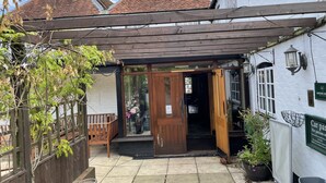 A traditional building with a wooden entrance, a covered patio area, and a sign indicating it is a pub. - The Swan Inn (Newbury)