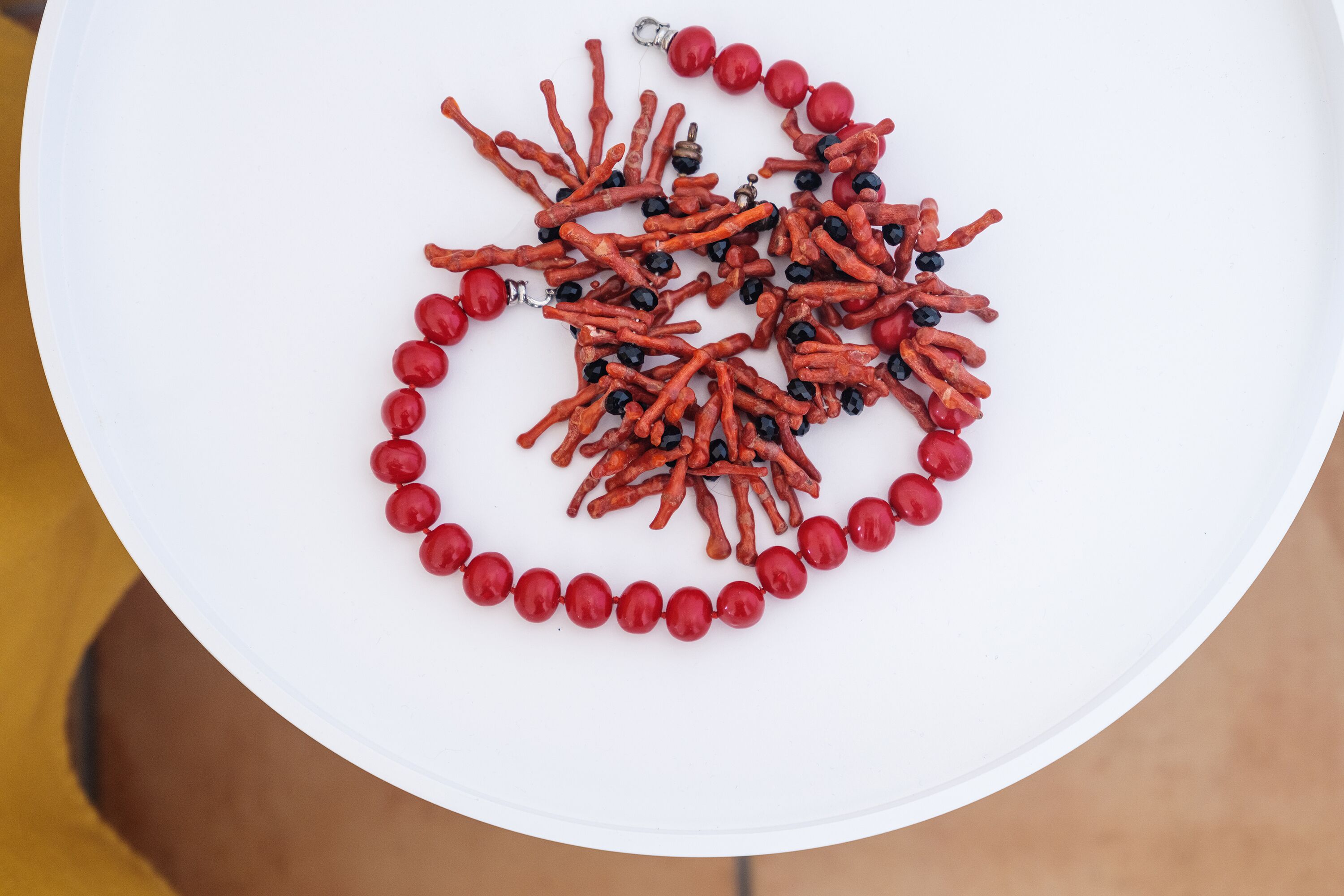 Un plat blanc amb un collar fet de grans vermells i negres.