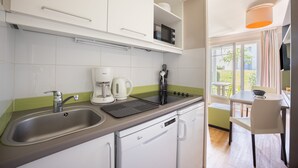 A modern kitchen with a sink, coffee maker, and microwave. There is a window with a view of the outside.