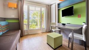 A room with a bed, a desk, a chair, a TV, and a window with curtains.