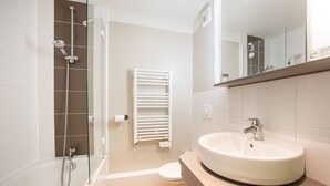 A modern bathroom with a bathtub, shower, toilet, and sink.