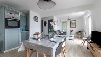 Une cuisine moderne avec des meubles de couleur bleu clair, un four encastré et un coin repas avec une table dressée pour six personnes.