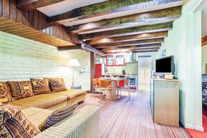 A cozy living room with a sofa, a dining table, and a kitchen area with appliances.