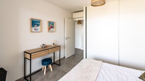 Un dormitorio con cama, escritorio y dos carteles en la pared.