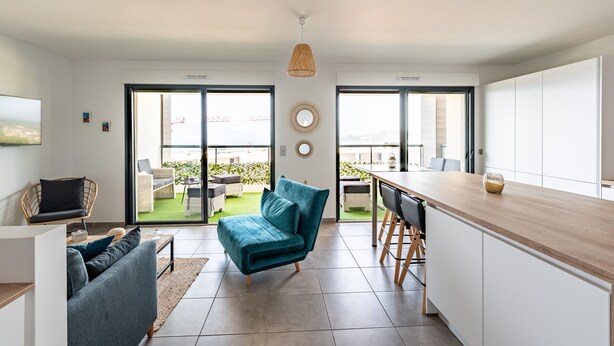 Una sala moderna con un sofá, una mesa de comedor y una zona de cocina con encimera de madera.