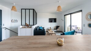 Una sala de estar moderna con una mesa de comedor de madera, un sofá y un televisor montado en la pared.