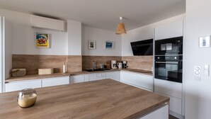 Una cocina moderna con encimera de madera, armarios blancos y horno integrado.