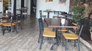Un restaurante con suelo de madera, sillas negras y de madera, y lámparas colgantes.