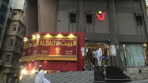 Een hotel met een opvallend bord waarop "NORAN HOTEL" staat, en een nabijgelegen AlBait AlBait Shawarma restaurant.