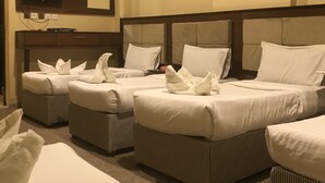 Een hotelkamer met vier bedden, een televisie en een spiegel aan de muur.