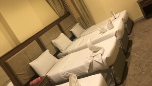 Een hotelkamer met twee bedden, een houten hoofdeinde, een nachtkastje en een vloerbedekking.